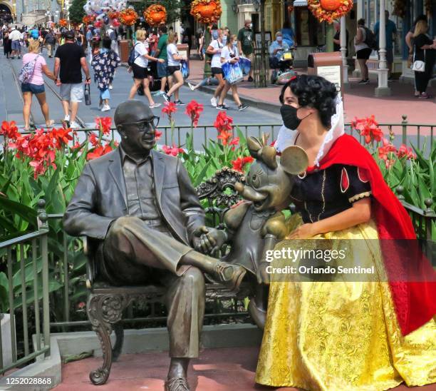 Guest dons a Snow White costume on Main Street, U.S.A., next to a statue of Roy O. Disney and Minnie Mouse, in the Magic Kingdom at Walt Disney...