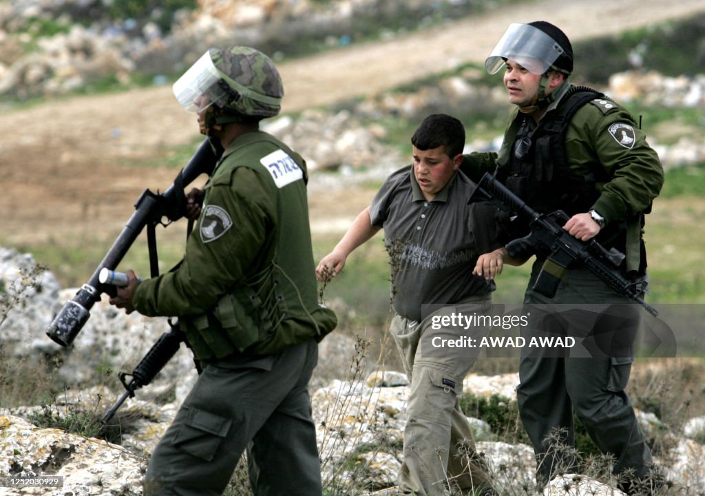 A young Palestinian stonethrower is dragged away by Israeli border ...