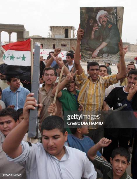 Iraqis in ousted dictator Saddam Hussein's hometown of Tikrit carry a portrait of their native son as they protest the guilty verdict and death...