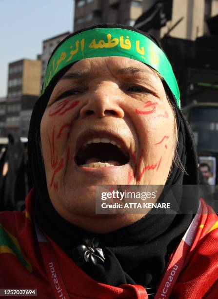 Iranian woman with anti-US and Israel slogans on her face, takes part in the funeral of Iranian nuclear scientist Mostafa Ahmadi-Roshan in Tehran on...