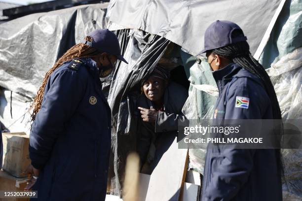 South Africa Immigration officers speak to a foreign migrant before she is evicted from a temporary dwelling built in front of the United Nations...