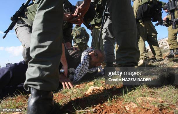 Palestinian man is held down by Israeli security, one of whom is holding a form of pepper spray, close to the Palestinian village of Beit Omar, in...