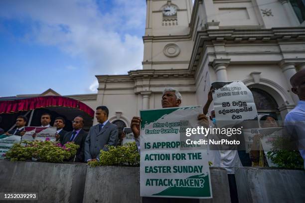 People hold placards in front of St. Anthony's shrine in Kochchikade for justice for the 2019 Easter bombing victims on April 21 in Colombo, Sri...