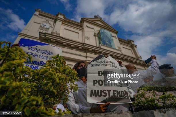 People hold placards in front of St. Anthony's shrine in Kochchikade for justice for the 2019 Easter bombing victims on April 21 in Colombo, Sri...