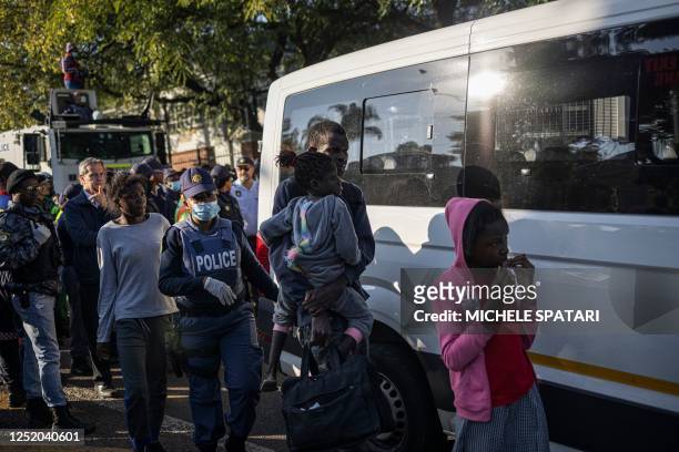 Member of the South African Police Service escorts foreign migrants after being evicted from a temporary dwelling built in front of the United...