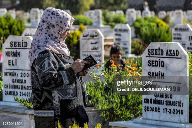 Woman reads from the Koran, Islam's holy book, before the grave of a fallen fighter of the Syrian Democratic Forces , as Muslims visit the graves of...