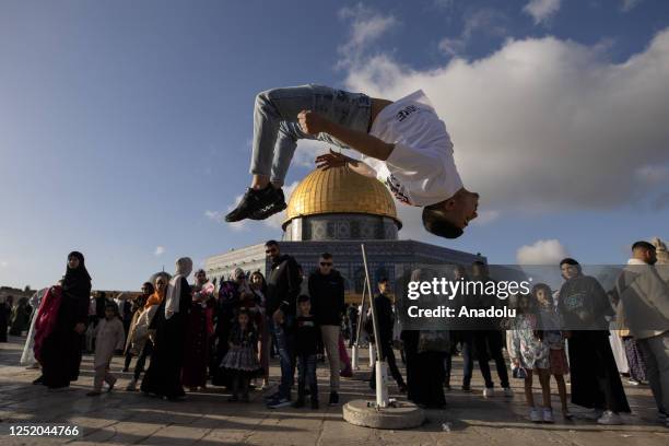 Boy performs a flip as Muslims exchange greetings in front of the Qubbat al-Sakhra after performing the Eid al-Fitr prayer at Masjid al-Aqsa Compound...