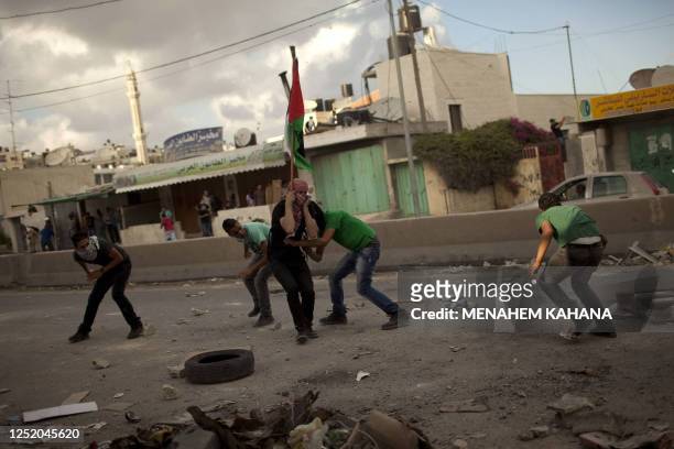 Palestinian stone throwers seek cover during clashes with Israeli soldiers at the Qalandia checkpoint between Jerusalem and Ramallah on September 23,...