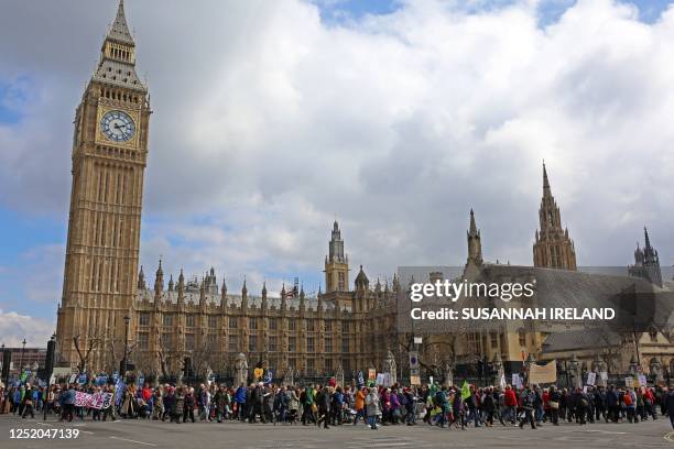 Protesters hold up placards as they march past the Palace of Westminster, home of the Houses of Parliament, in Westminster, central London at a...