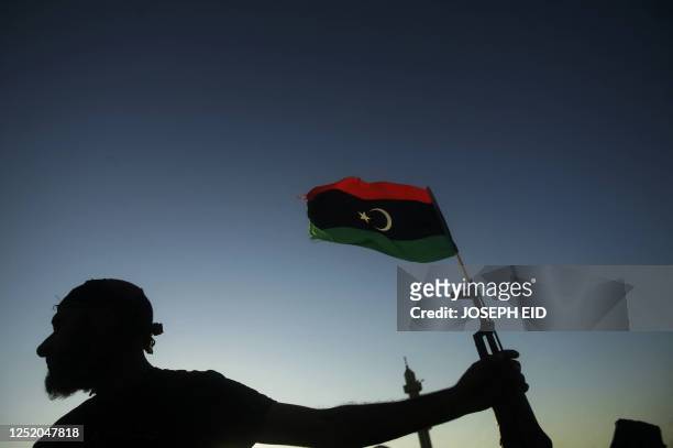 Libyan new regimes forces fighter holds a weapon with a Libyan flag as he secures an area on the frontline with the city of Bani-Walid on September...