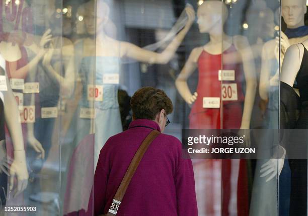 Woman looks at the price of dresses through a shop window in Mexico City, 27 January 2003. Una mujer mira los precios de vestidos, afichados en peso...