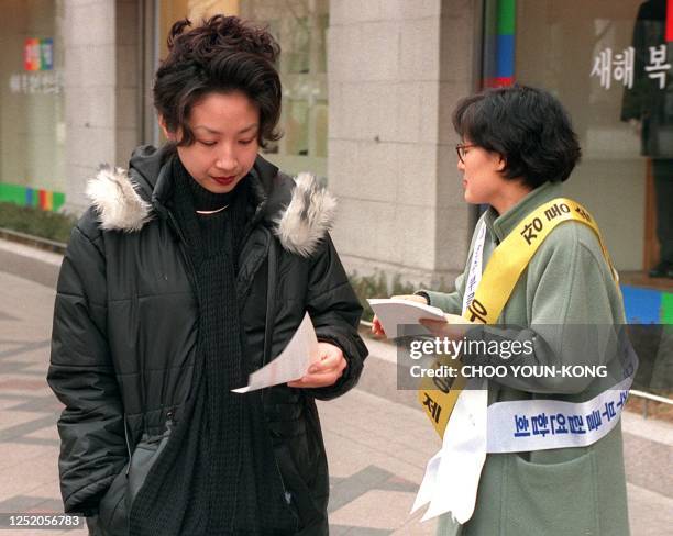 South Korean woman volunteer distributes leaflets to passers-by in a street of Seoul 07 January, asking for gold donations to help pull the country's...