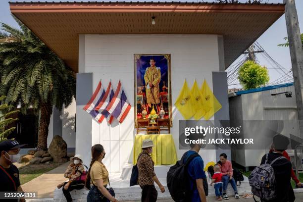 People arriving into Thailand from Cambodia walk past a portrait of King Maha Vajiralongkorn in the border town of Aranyaprathet on April 22, 2023.