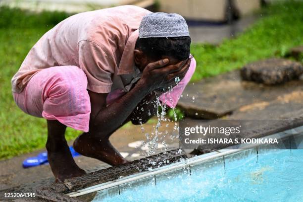 Muslim man performs ablution before offering a special morning prayer to start the Eid al-Fitr festival, which marks the end of their holy fasting...