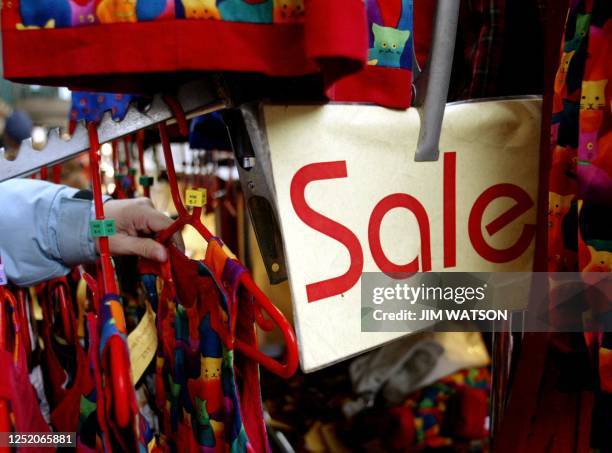 Woman reaches in to get a child's outfit at a shop at Covent Garden in London 23 January 2004 near a sale sign. The British economy powered ahead at...