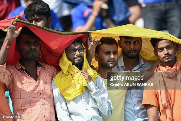 Spectators use scarfs to shelter from the heat during the Indian Premier League Twenty20 cricket match between Lucknow Super Giants and Gujarat...