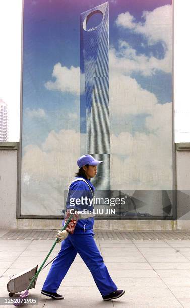 An environmental worker passes a large billboard showing the Shanghai World Financial Center in Shanghai's new economic district Pudong, 09 February...