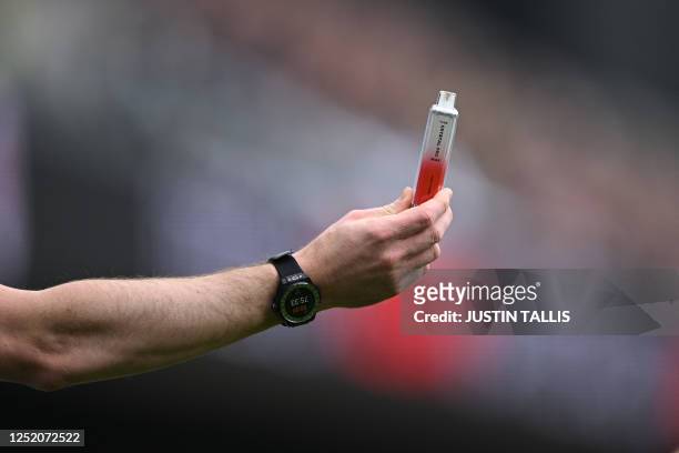 The assistant referee hands an e-cigarette to the referee, presumed thrown from the crowd onto the pitch during the English Premier League football...