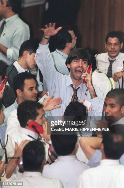 Trader at the Sao Paulo stock exchange shouts transactions over the phone in the middle of a pit during the morning session 06 October 1998 as the...