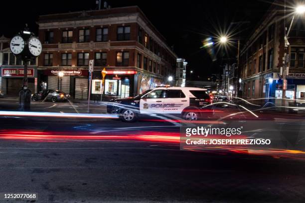 Cars speed by a parked police cruiser in Chelsea, Massachusetts, on April 21, 2023. - Chelsea is 2.2 square miles with a population of about 40,000...