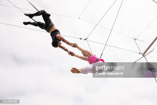 trapezkünstler fliegen gemeinsam am himmel - trapeze stock-fotos und bilder