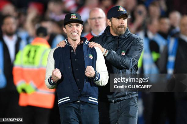 Actor and Wrexham owner Rob McElhenney and US actor and Wrexham owner Ryan Reynolds celebrate on the pitch after the English National League football...