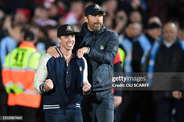 Actor and Wrexham owner Rob McElhenney and US actor and Wrexham owner Ryan Reynolds celebrate on the pitch after the English National League football...