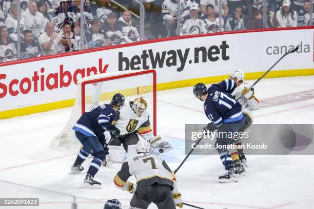 Vladislav Namestnikov and Adam Lowry of the Winnipeg Jets look for the loose puck as goaltender Laurent Brossoit of the Vegas Golden Knights attempts...