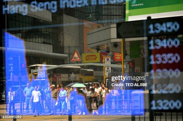 Pedestrians are reflected on a Hang Seng index electronic monitor displayed outside a bank in Hong Kong on October 24. 2008. Hong Kong share prices...