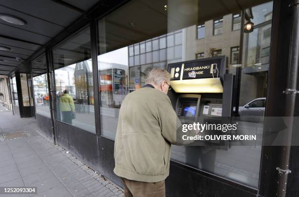 Man takes money from an automatic teller machine outside the Icelandic bank Kaupping on October 8, 2008 in Rejkjavik. The Icelandic state has...