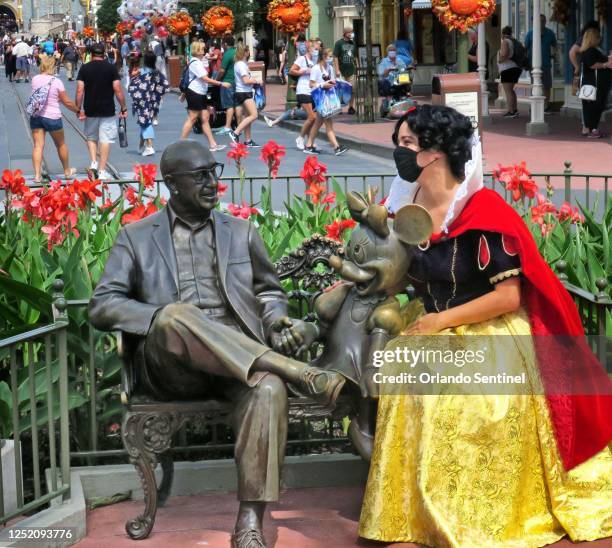 Guest dons a Snow White costume on Main Street, U.S.A., next to a statue of Roy O. Disney and Minnie Mouse, in the Magic Kingdom at Walt Disney...