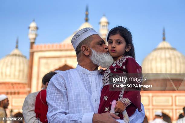 Muslim man plays with his kid at Jama Masjid mosque on Eid al-Fitr festival. Eid Al-Fitr is a festival that marks the end of the Muslim holy month of...