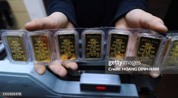 Local gold shop's employee shows off gold bars in Hanoi on February 25, 2011. According to the local official media, the Vietnamese government is...