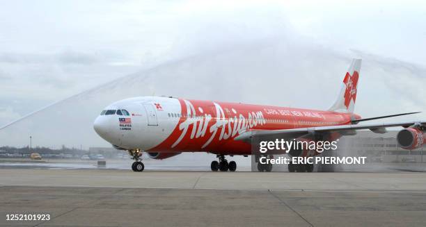 Malaysia's long-haul budget airline AirAsia X Airbus A340 jetliner is greeted with jets of water upon its landing at the end of the AirAsia X first...