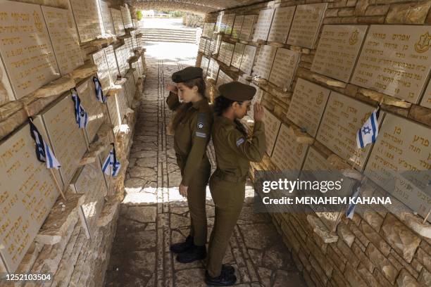 Israeli soldiers render the hand salute after laying national flags with black ribbons on the graves of Israeli soldiers at the Mount Herzl military...