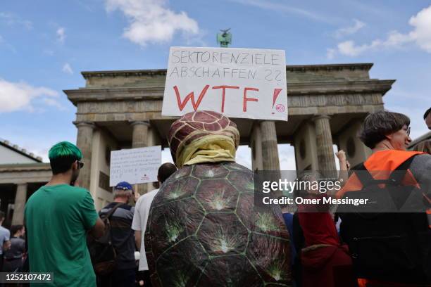 Participant with a sea turtle costume holds a banner as activists of the "Last Generation" climate action movement protest at the Brandenburg Gate...