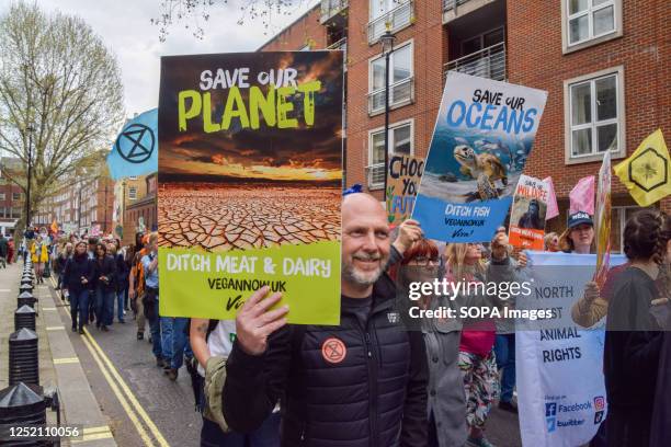 Protester holds a placard urging people to go vegan to save the planet, during the demonstration. Thousands of people marched through Westminster in...