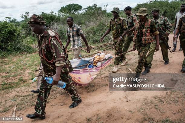 Security personnel carry a rescued young person from the forest in Shakahola, outside the coastal town of Malindi, on April 23, 2023. - Twenty-one...