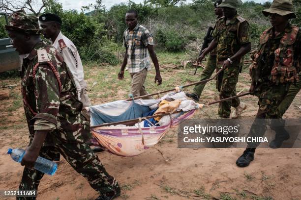 Security personnel carry a rescued young person from the forest in Shakahola, outside the coastal town of Malindi, on April 23, 2023. - Twenty-one...