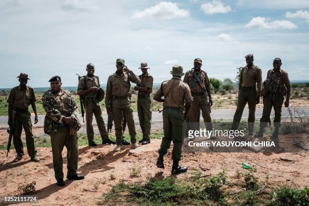 Security personnel gather at the entrance of the forest to the site that buried bodies have been exhumed in Shakahola, outside the coastal town of...