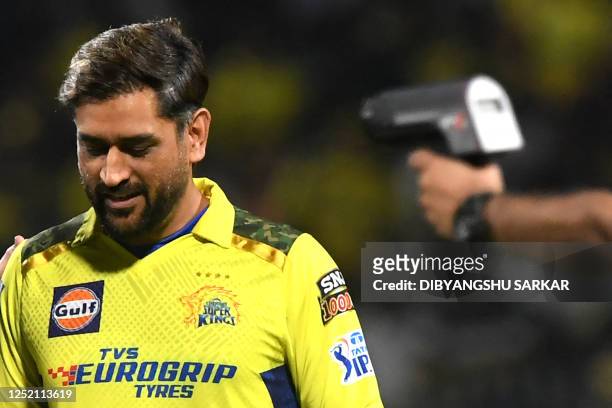 Chennai Super Kings' captain Mahendra Singh Dhoni watches as an official uses a radar speed gun before the start of the Indian Premier League...
