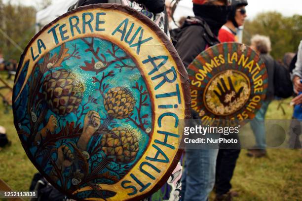 Protesters before the beginning of the 12km march against the planned a69 highway. Shields read 'Earth to artichokes' and 'We're the living who...