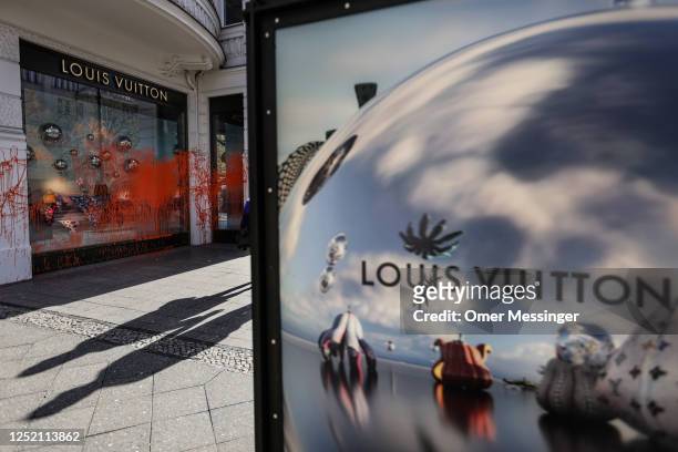 Orange paint sprayed by activists from the "Last Generation" climate action movement the display window of a LOUIS VUITTON shop on the famous...