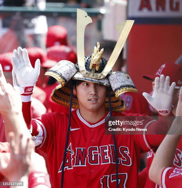 Shohei Ohtani of the Los Angeles Angels, wearing a kabuto helmet, celebrates with teammates in the dugout after hitting a solo homer during the sixth...