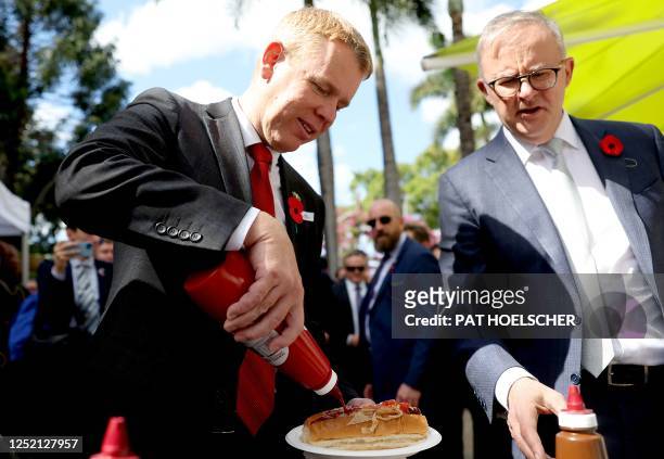 New Zealand's Prime Minister Chris Hipkins adds tomato ketchup to a hotdog beside Australia's Prime Minister Anthony Albanese after the citizenship...
