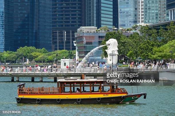 People take pictures on the jetty in front of Merlion Statue at Marina bay in Singapore on April 24, 2023.