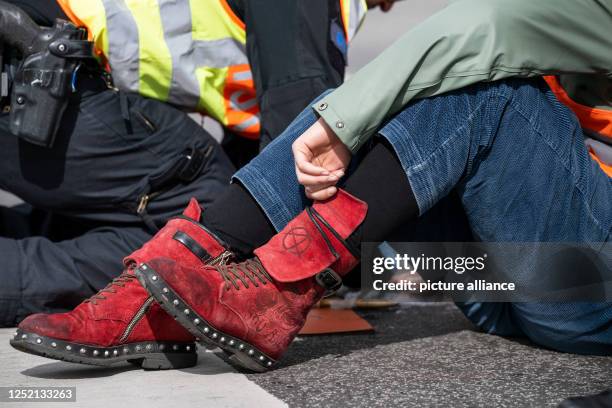 April 2023, Berlin: An activist wears a shoe with an anarchy symbol during the blockade of the intersection Berliner Straße - Konstanzer Straße. On...