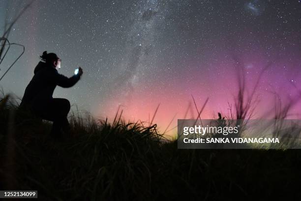 Man takes pictures of the Aurora Australis, also known as the Southern Lights, as it glows on the horizon over waters of Lake Ellesmere on the...