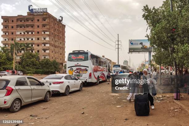 People prepare to board a bus departing from Khartoum in the Sudanese capital's south on April 24 as battles rage in the city between the army and...