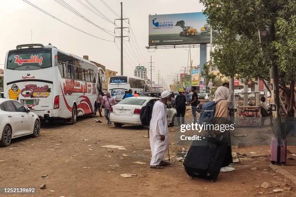 People prepare to board a bus departing from Khartoum in the Sudanese capital's south on April 24 as battles rage in the city between the army and...